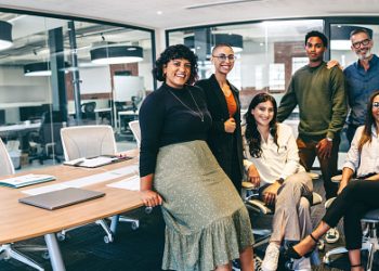 Team of businesspeople smiling at the camera in a boardroom. Cheerful businesspeople grouped together in a modern workplace. Diverse team of businesspeople looking cheerful.